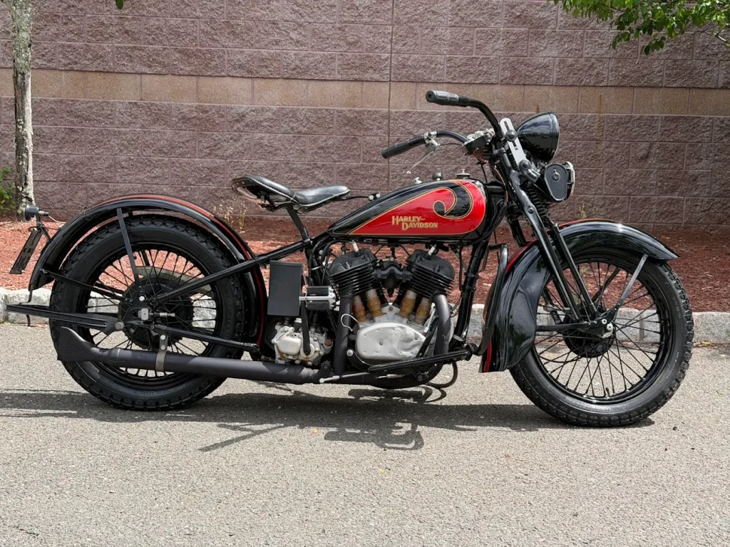 Uma rara Harley-Davidson VLD de 1931, sem restauro e com a pátina do tempo, anteriormente pertencente ao lendário ator e entusiasta de motocicletas Steve McQueen, exibida em um ambiente de leilão, destacando sua autenticidade e condição original e histórica.