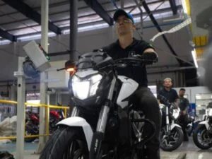Linha de montagem da fábrica da Bajaj em Manaus, com trabalhadores inspecionando motocicletas Dominar 400 em produção, destacando a eficiência e o volume de veículos montados.