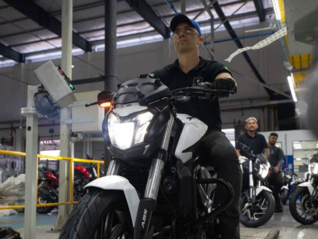 Linha de montagem da fábrica da Bajaj em Manaus, com trabalhadores inspecionando motocicletas Dominar 400 em produção, destacando a eficiência e o volume de veículos montados.