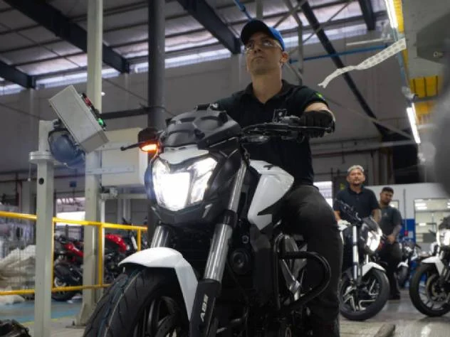 Linha de montagem da fábrica da Bajaj em Manaus, com trabalhadores inspecionando motocicletas Dominar 400 em produção, destacando a eficiência e o volume de veículos montados.