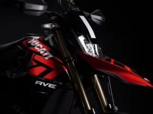 Uma Ducati Hypermotard 698 Mono em destaque, exibindo seu design agressivo e esportivo, com o motor Superquadro Mono visível e pronta para a pilotagem, sob um céu claro.