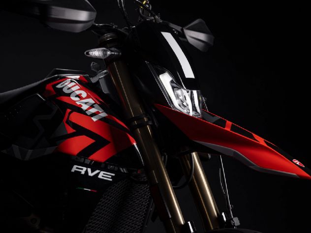 Uma Ducati Hypermotard 698 Mono em destaque, exibindo seu design agressivo e esportivo, com o motor Superquadro Mono visível e pronta para a pilotagem, sob um céu claro.
