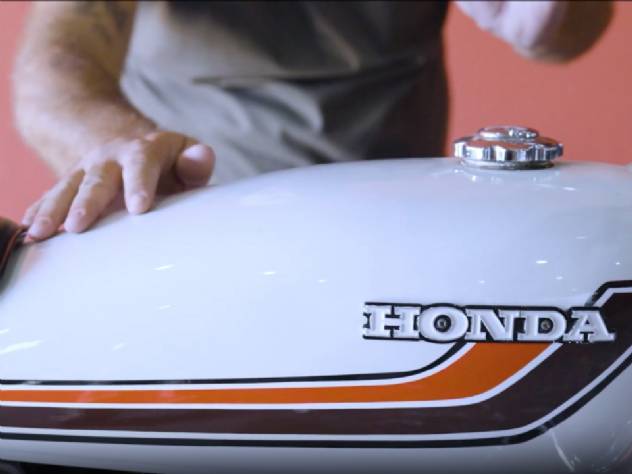 Homem de capacete e equipamento de segurança sobre uma motocicleta Honda CG 160 vermelha, comemorando os 50 anos do modelo no Brasil, simbolizando a longa trajetória e popularidade da moto.