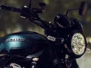 Kawasaki Z900RS 2027 vermelha em ambiente urbano, destacando seu design clássico e moderno, com farol redondo de LED e detalhes cromados.