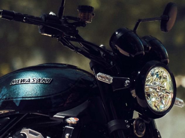 Kawasaki Z900RS 2027 vermelha em ambiente urbano, destacando seu design clássico e moderno, com farol redondo de LED e detalhes cromados.