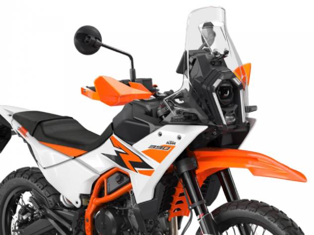 Motocicleta KTM 390 Adventure em trilha de terra com paisagem montanhosa ao fundo, destacando seu design aventureiro e capacidade off-road.