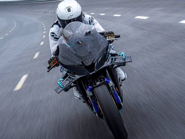 Detalhe de um protótipo de motocicleta superesportiva CFMOTO V4 SR-RR, com linhas aerodinâmicas agressivas, carenagem em fibra de carbono e detalhes em vermelho e cinza, transmitindo alta velocidade e tecnologia de ponta em um ambiente de pista de testes.
