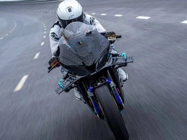 Detalhe de um protótipo de motocicleta superesportiva CFMOTO V4 SR-RR, com linhas aerodinâmicas agressivas, carenagem em fibra de carbono e detalhes em vermelho e cinza, transmitindo alta velocidade e tecnologia de ponta em um ambiente de pista de testes.