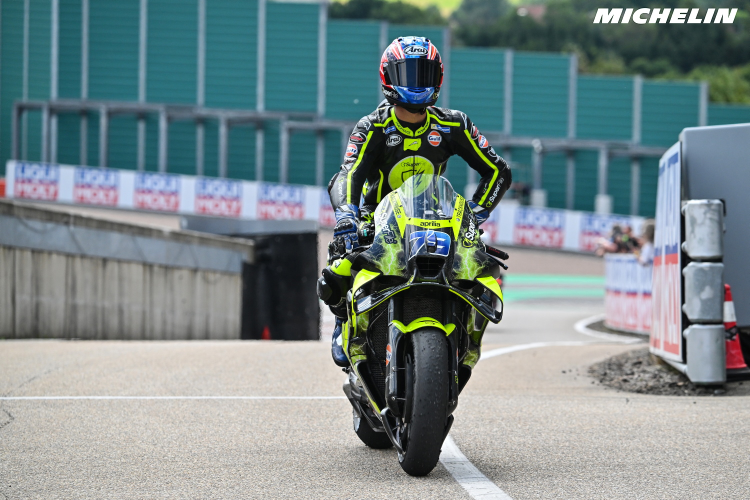 Ai Ogura, piloto japonês da Trackhouse Racing, celebrando um de seus três pódios consecutivos na temporada de MotoGP, mostrando sua Aprilia RS-GP.