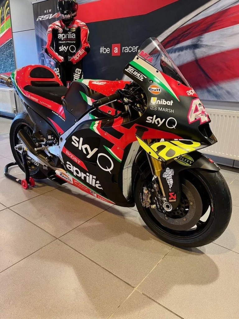Aprilia RS-GP20 de corrida, uma motocicleta de MotoGP em plena pista, pilotada por Aleix Espargaró, destacando seu design aerodinâmico e a pintura de fábrica.