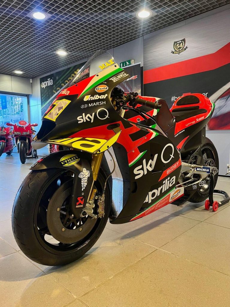 Aprilia RS-GP20 de corrida, uma motocicleta de MotoGP em plena pista, pilotada por Aleix Espargaró, destacando seu design aerodinâmico e a pintura de fábrica.