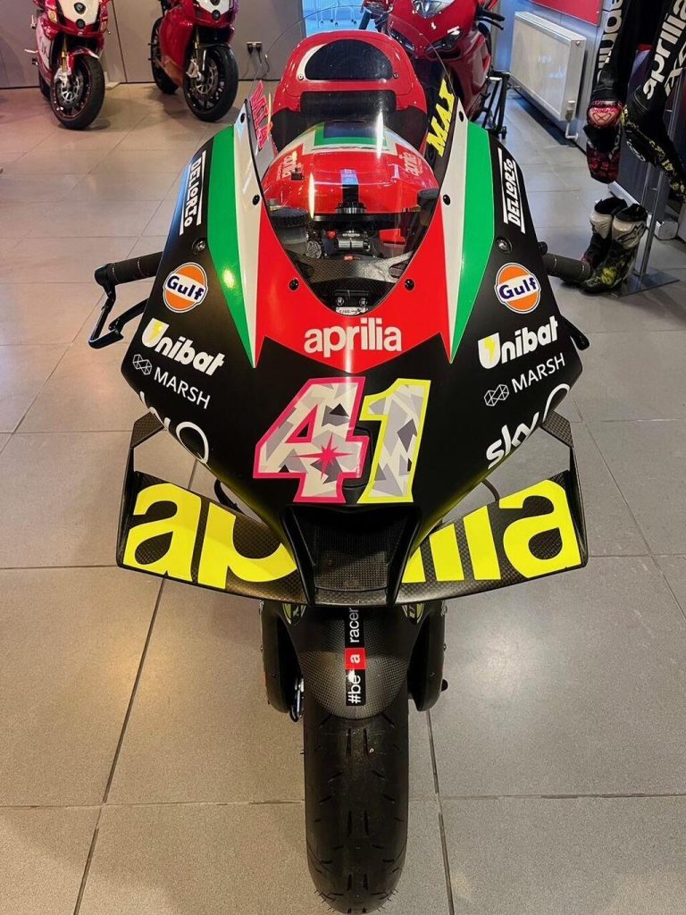 Aprilia RS-GP20 de corrida, uma motocicleta de MotoGP em plena pista, pilotada por Aleix Espargaró, destacando seu design aerodinâmico e a pintura de fábrica.