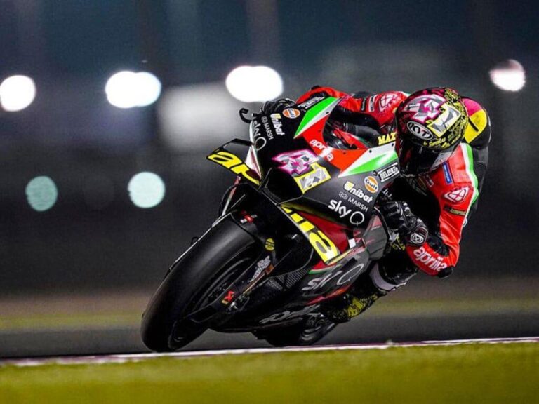 Aprilia RS-GP20 de corrida, uma motocicleta de MotoGP em plena pista, pilotada por Aleix Espargaró, destacando seu design aerodinâmico e a pintura de fábrica.