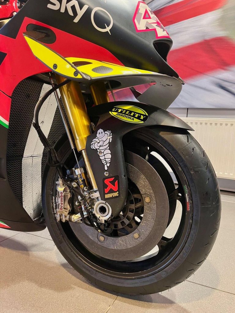 Aprilia RS-GP20 de corrida, uma motocicleta de MotoGP em plena pista, pilotada por Aleix Espargaró, destacando seu design aerodinâmico e a pintura de fábrica.