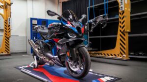 BMW M 1000 RR 2027 em alta velocidade na pista, exibindo seu design aerodinâmico e novas cores vibrantes, simbolizando as atualizações da linha de motos BMW.
