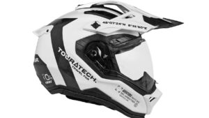 Motociclista usando o Capacete Touratech Aventuro Gravel Carbon em uma paisagem de montanhas, destacando seu design robusto e leveza para aventura.