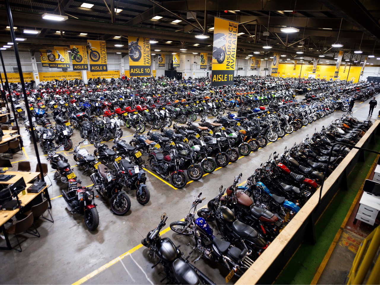 Fachada de uma grande concessionária de motos SuperBike Factory com diversos modelos expostos, retratando seu auge.