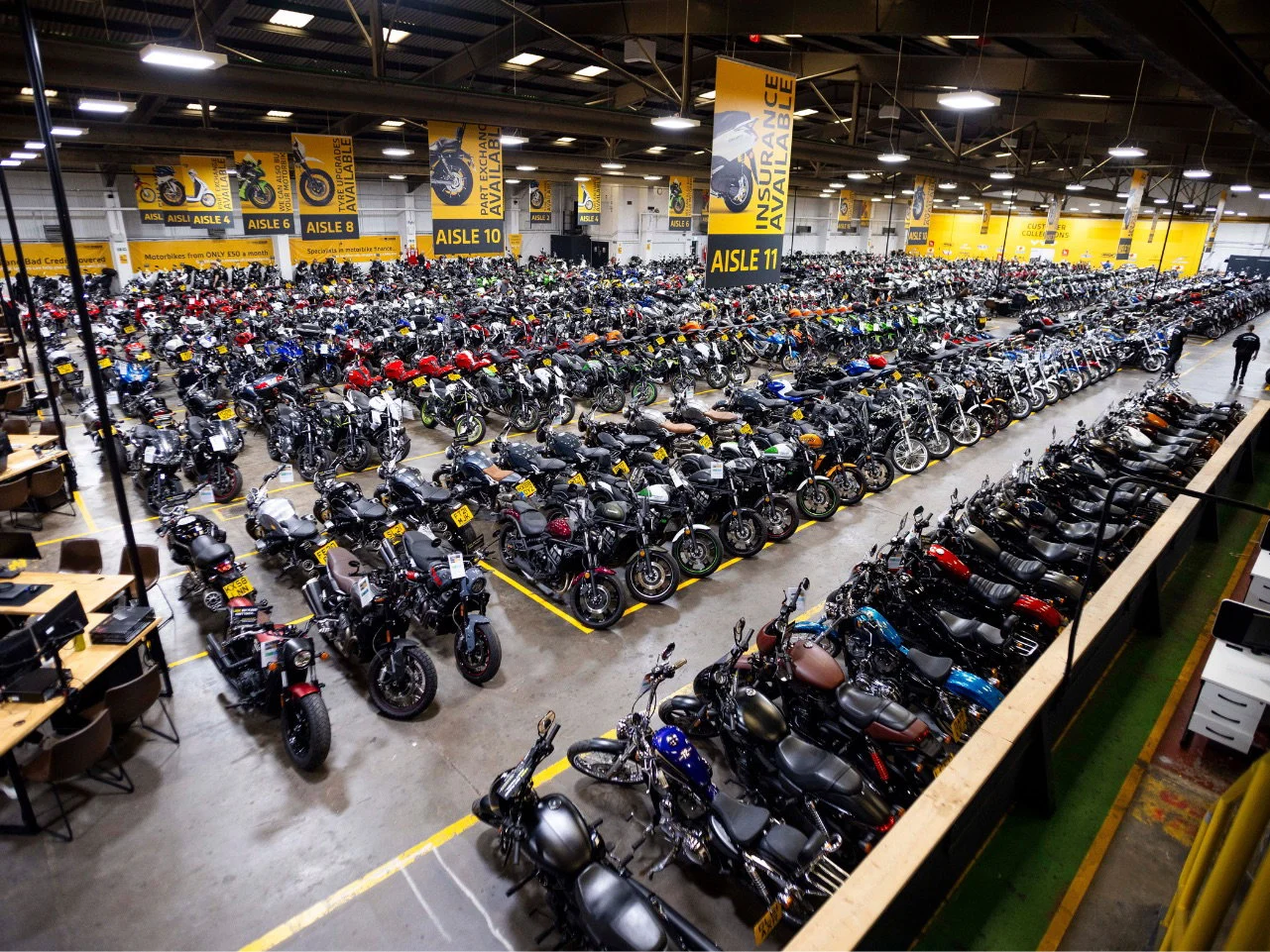 Fachada de uma grande concessionária de motos SuperBike Factory com diversos modelos expostos, retratando seu auge.