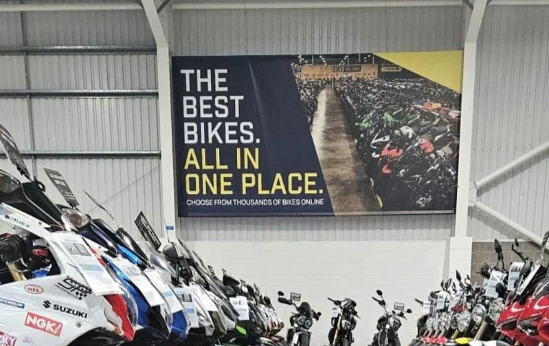 Fachada de uma grande concessionária de motos SuperBike Factory com diversos modelos expostos, retratando seu auge.