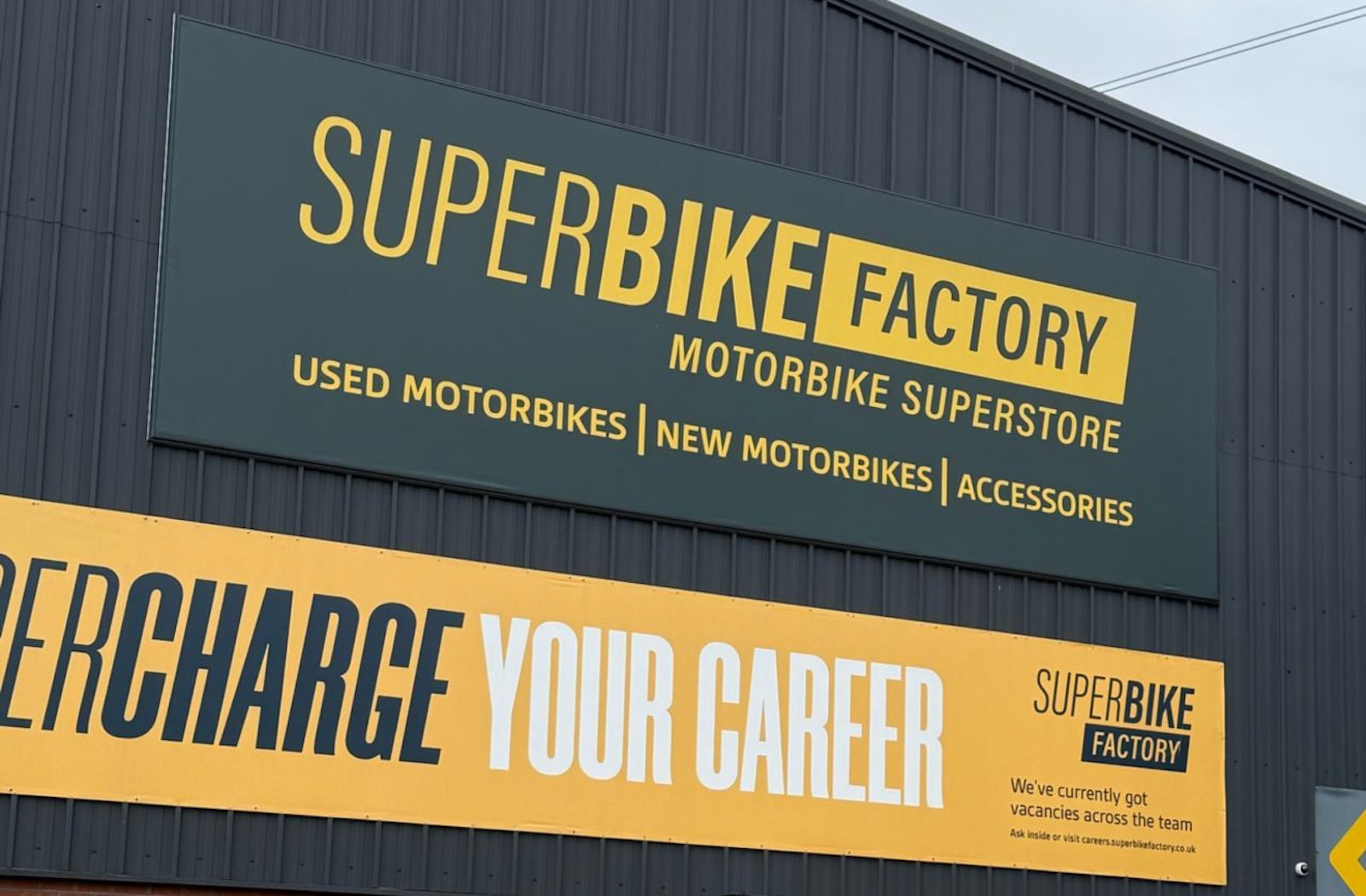 Fachada de uma grande concessionária de motos SuperBike Factory com diversos modelos expostos, retratando seu auge.