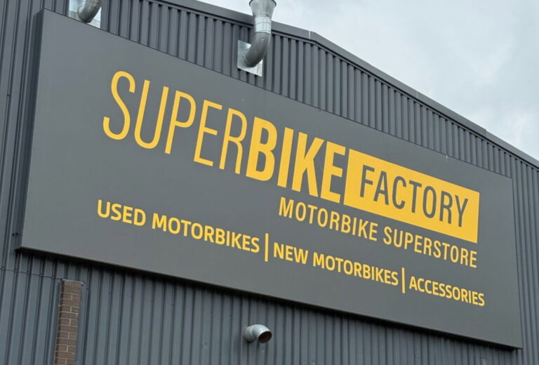 Fachada de uma grande concessionária de motos SuperBike Factory com diversos modelos expostos, retratando seu auge.