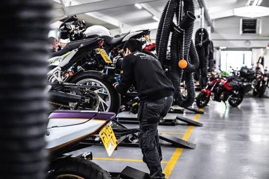 Vista panorâmica de uma grande concessionária de motocicletas usadas, SuperBike Factory, com centenas de motos de diversas marcas e modelos expostas no showroom. Detalhe da organização e iluminação do espaço.