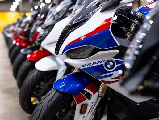 Vista panorâmica de uma grande concessionária de motocicletas usadas, SuperBike Factory, com centenas de motos de diversas marcas e modelos expostas no showroom. Detalhe da organização e iluminação do espaço.