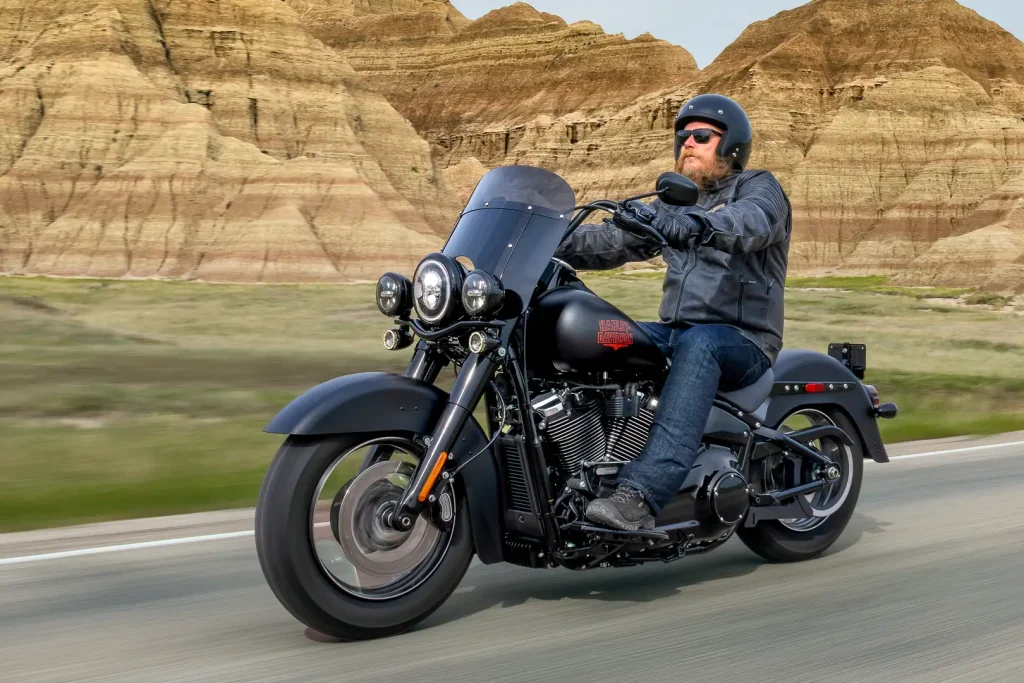 Harley-Davidson Deadwood 2026 estacionada, destacando seu acabamento Denim Black e o design clássico da linha Softail, ideal para pilotos que buscam tradição.