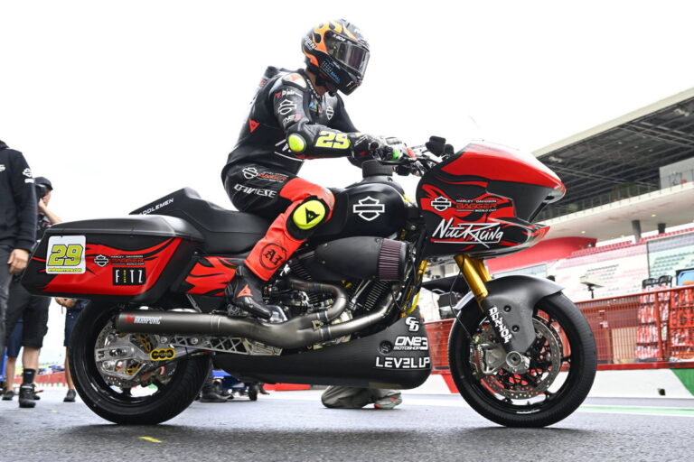 Motocicletas Harley-Davidson Bagger personalizadas competindo em uma pista, com fãs assistindo e o logotipo do MotoGP ao fundo, destacando a emoção do evento.