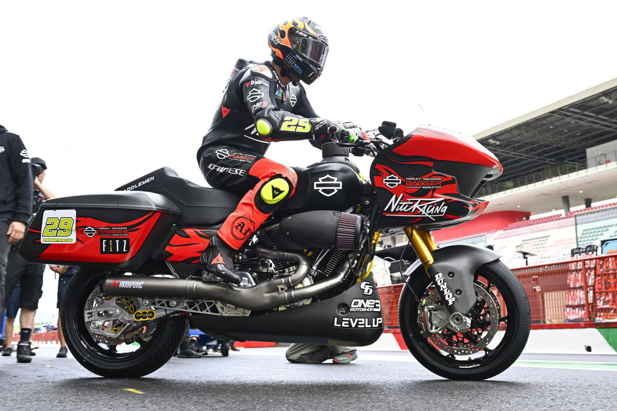 Motocicletas Harley-Davidson Bagger personalizadas competindo em uma pista, com fãs assistindo e o logotipo do MotoGP ao fundo, destacando a emoção do evento.