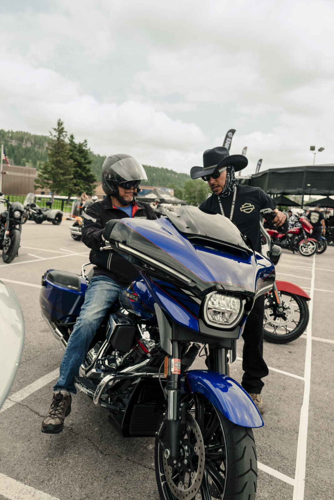 Multidão de motociclistas em suas Harley-Davidson reunidos durante a Sturgis Motorcycle Rally, com a paisagem das Black Hills ao fundo.