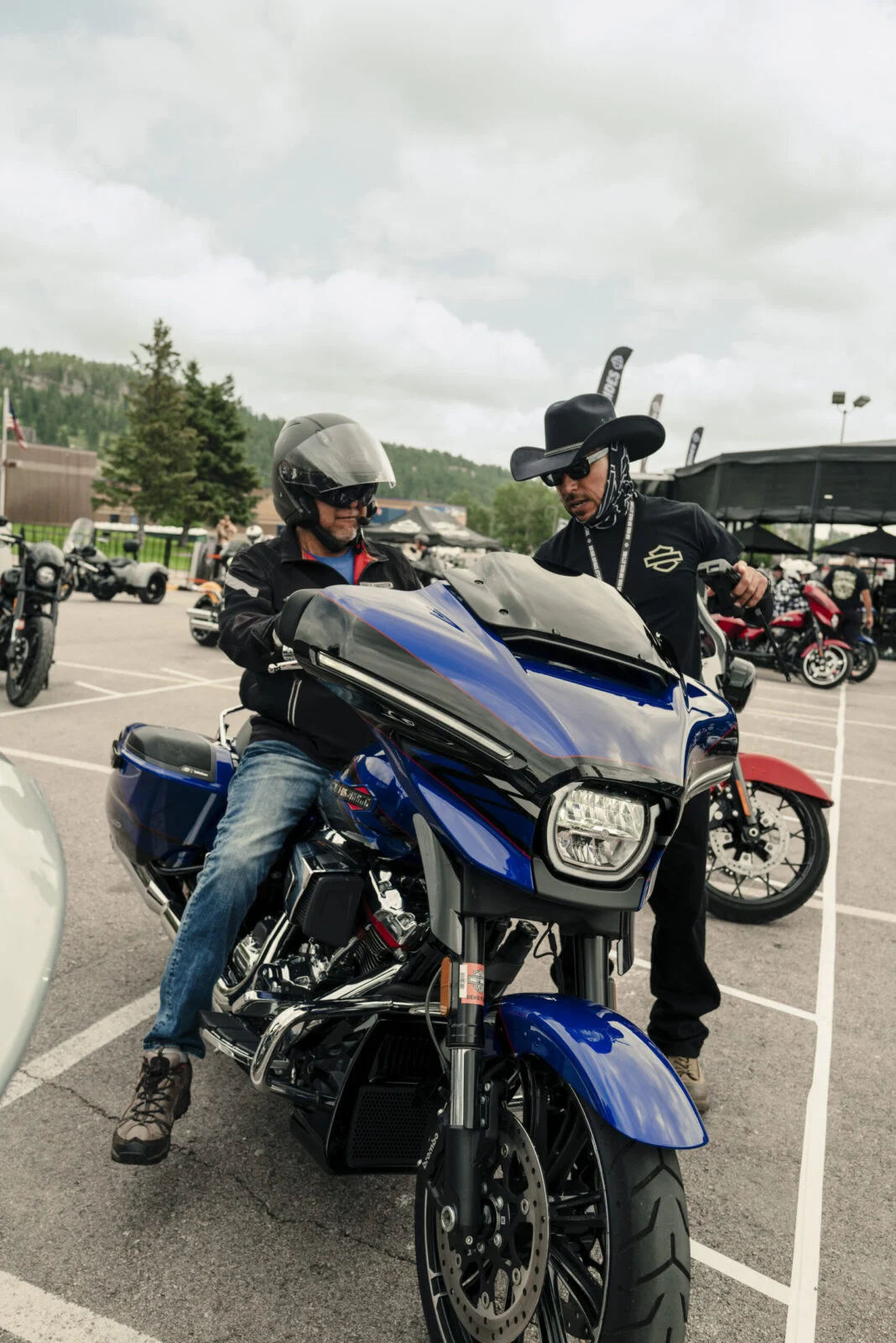 Multidão de motociclistas em suas Harley-Davidson reunidos durante a Sturgis Motorcycle Rally, com a paisagem das Black Hills ao fundo.