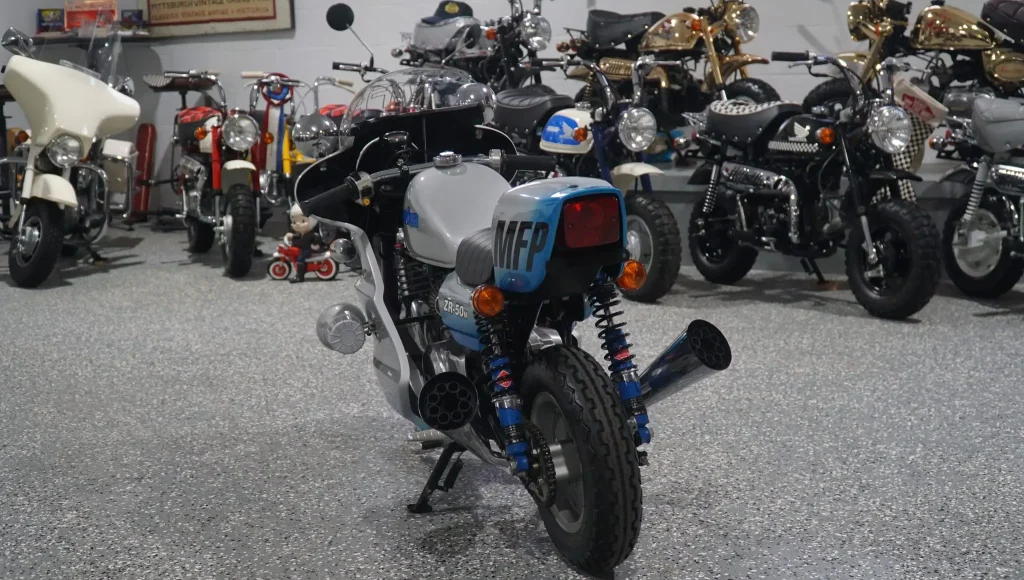 Honda Monkey 1986 customizada no estilo Mad Max, com pintura preta e detalhes cromados, inspirada na lendária motocicleta de Jim Goose, o policial de Mad Max.