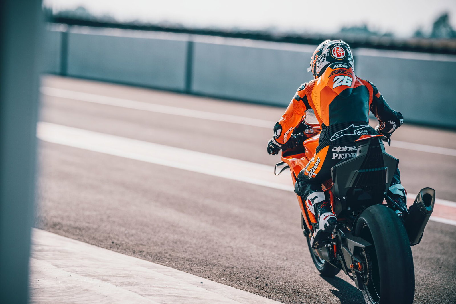 Moto esportiva KTM em alta velocidade em pista de corrida, destacando design agressivo e performance que remete ao MotoGP.