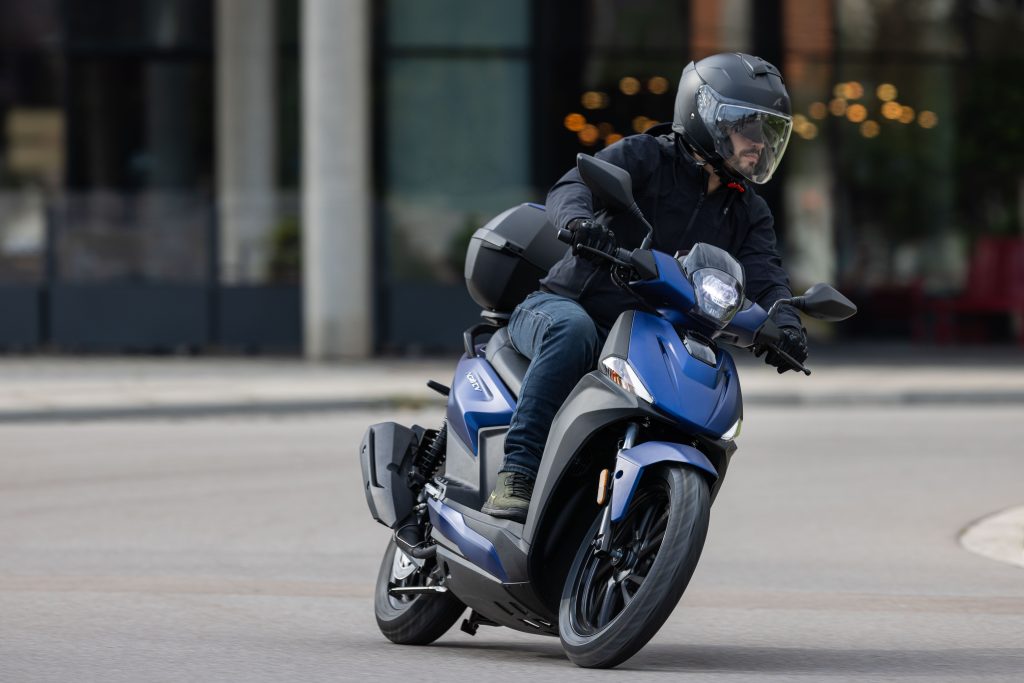 Kymco Agility 125 NX 2024 estacionada em ambiente urbano, exibindo seu design moderno e iluminação LED, destacando as rodas de liga leve e a ergonomia otimizada para o dia a dia.