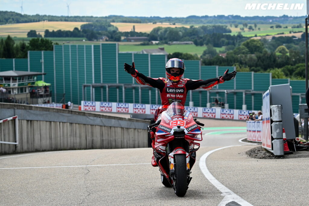 Marc Márquez acelerando sua moto Ducati da equipe Gresini em plena curva durante uma corrida de MotoGP, com foco em sua pilotagem agressiva e precisa.