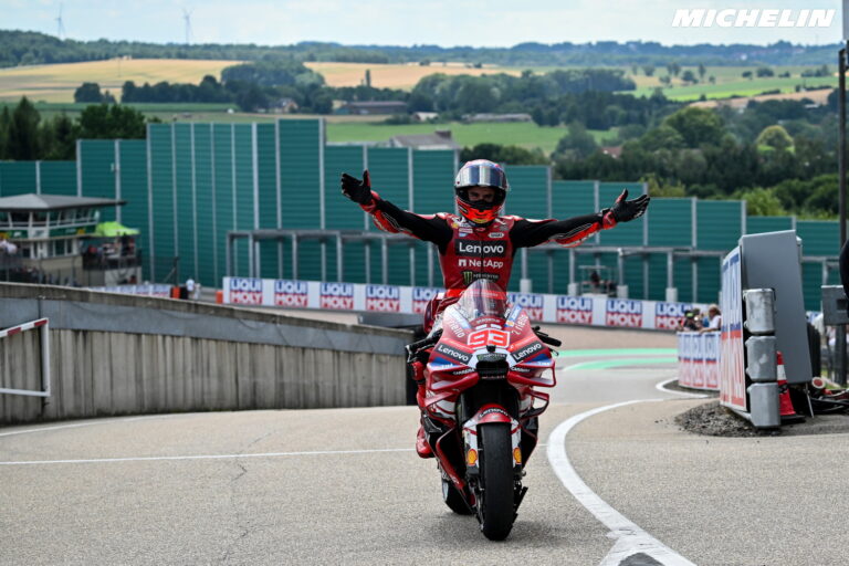 Marc Márquez acelerando sua moto Ducati da equipe Gresini em plena curva durante uma corrida de MotoGP, com foco em sua pilotagem agressiva e precisa.