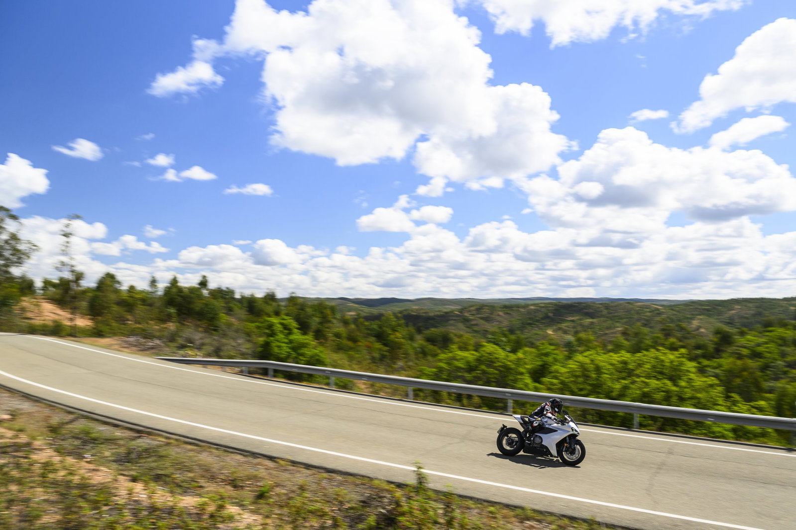 Motocicleta em uma estrada sinuosa nas montanhas dos Pireneus na Espanha, ao pôr do sol, destacando a beleza das melhores viagens de moto na Europa.
