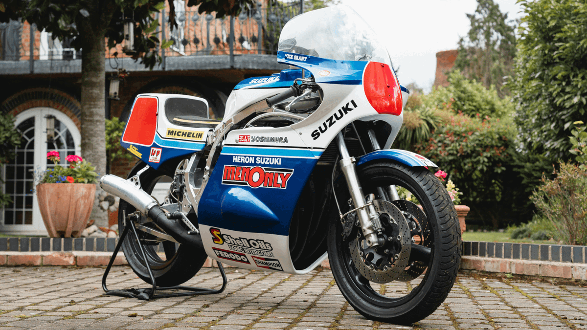 Mick Grant a bordo de sua icônica Heron Suzuki GS1000R de competição no lendário circuito do Isle of Man TT, uma moto de corrida histórica e de alto desempenho.