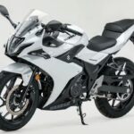 Vista lateral de uma Suzuki GSX250R esportiva, em movimento na estrada, destacando seu design aerodinâmico e as rodas.