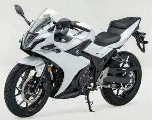 Vista lateral de uma Suzuki GSX250R esportiva, em movimento na estrada, destacando seu design aerodinâmico e as rodas.