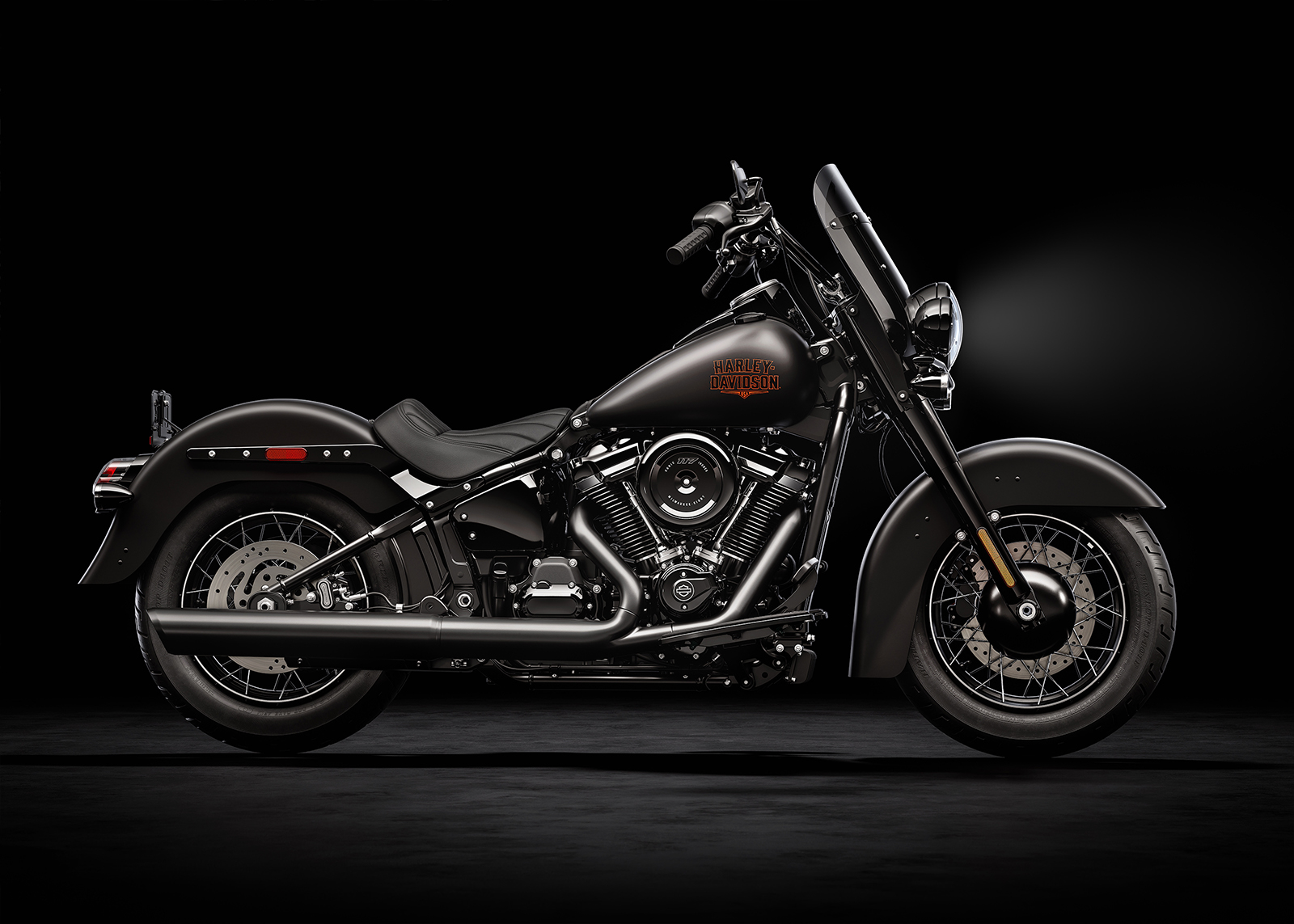 Renderização conceitual de uma motocicleta Harley-Davidson Deadwood estilo bobber retro em uma estrada sinuosa, com farol único e banco solo, em tons escuros e cromados.