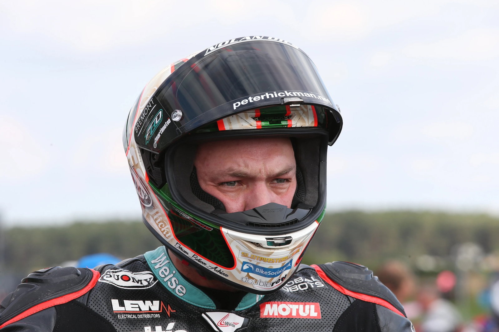 Peter Hickman se preparando para pilotar a lendária moto de corrida Norton Rotary na Snaefell Mountain Course do Classic TT, destacando o motor Wankel e seu design clássico de corrida.