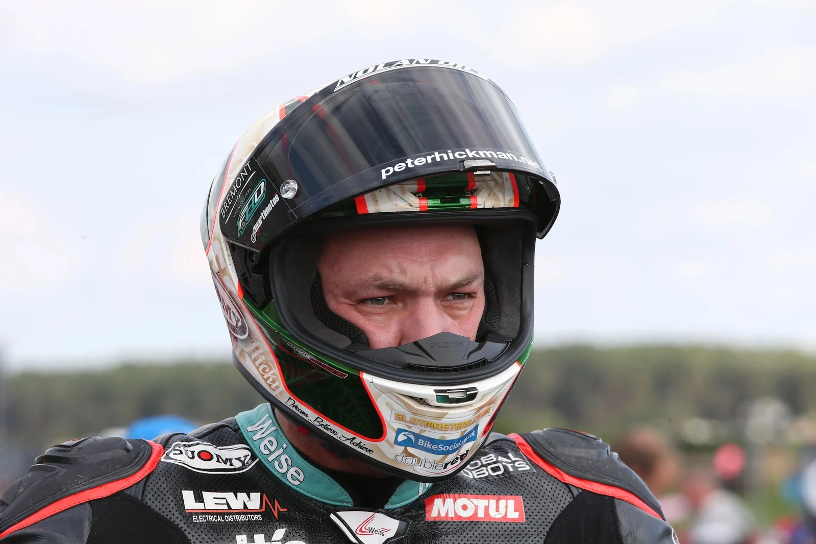 Peter Hickman se preparando para pilotar a lendária moto de corrida Norton Rotary na Snaefell Mountain Course do Classic TT, destacando o motor Wankel e seu design clássico de corrida.