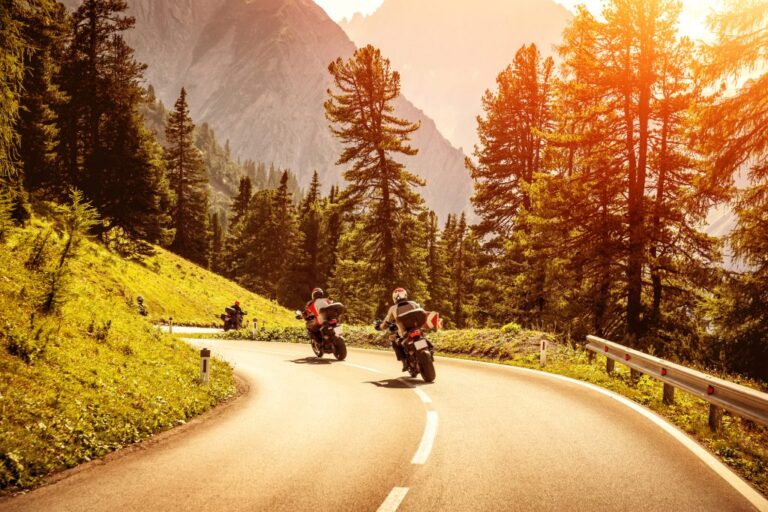 Motociclista com equipamento completo pilotando sua moto em uma estrada ensolarada durante o verão, destacando a importância da segurança