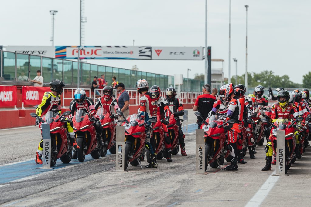 Ducati Panigale V4 R em pista durante o evento DRE Racetrack, com um piloto em inclinação máxima, demonstrando a pilotagem esportiva e a performance da motocicleta.