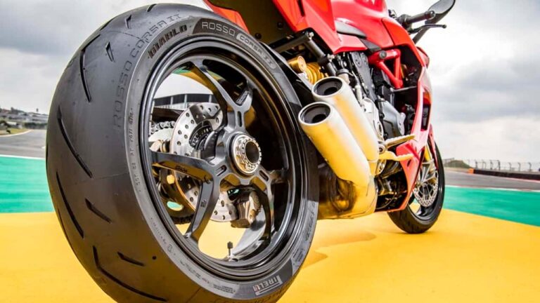 Pneus Pirelli de motocicleta exibindo o processo de reciclagem, com materiais compostos e sustentáveis ao fundo, simbolizando inovação ambiental.