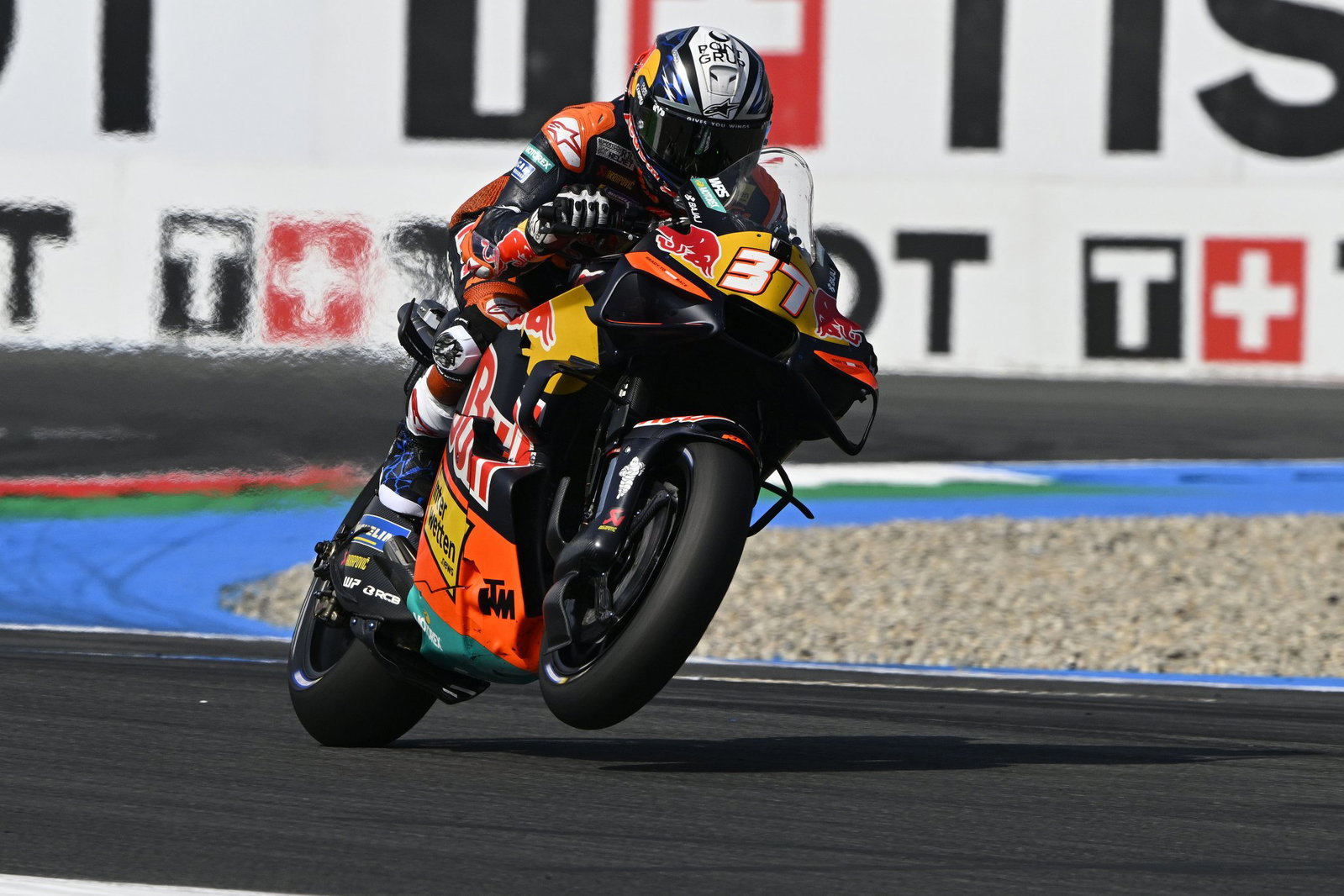 Duas motos KTM RC16 da equipe Red Bull KTM Factory Racing em plena ação na pista de MotoGP, mostrando a potência e a aerodinâmica das máquinas de corrida, mas enfrentando problemas de motor.