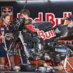 Duas motos KTM RC16 da equipe Red Bull KTM Factory Racing em plena ação na pista de MotoGP, mostrando a potência e a aerodinâmica das máquinas de corrida, mas enfrentando problemas de motor.
