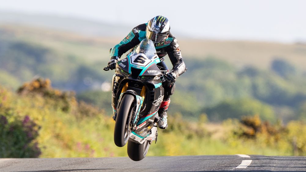 Michael Dunlop em sua moto de corrida em alta velocidade durante o Isle of Man TT, demonstrando sua perícia nas desafiadoras estradas.